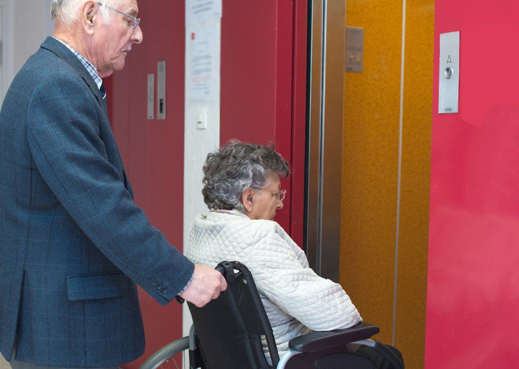 un couple de personnes agées rentre dans un ascenceur 
