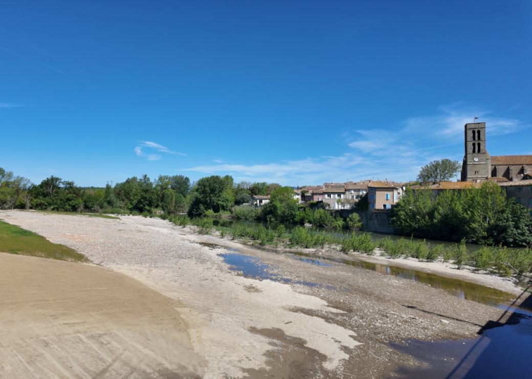 un cours d'eau bordé par un village. L'eau coule au milieu d'une très large bande de sable