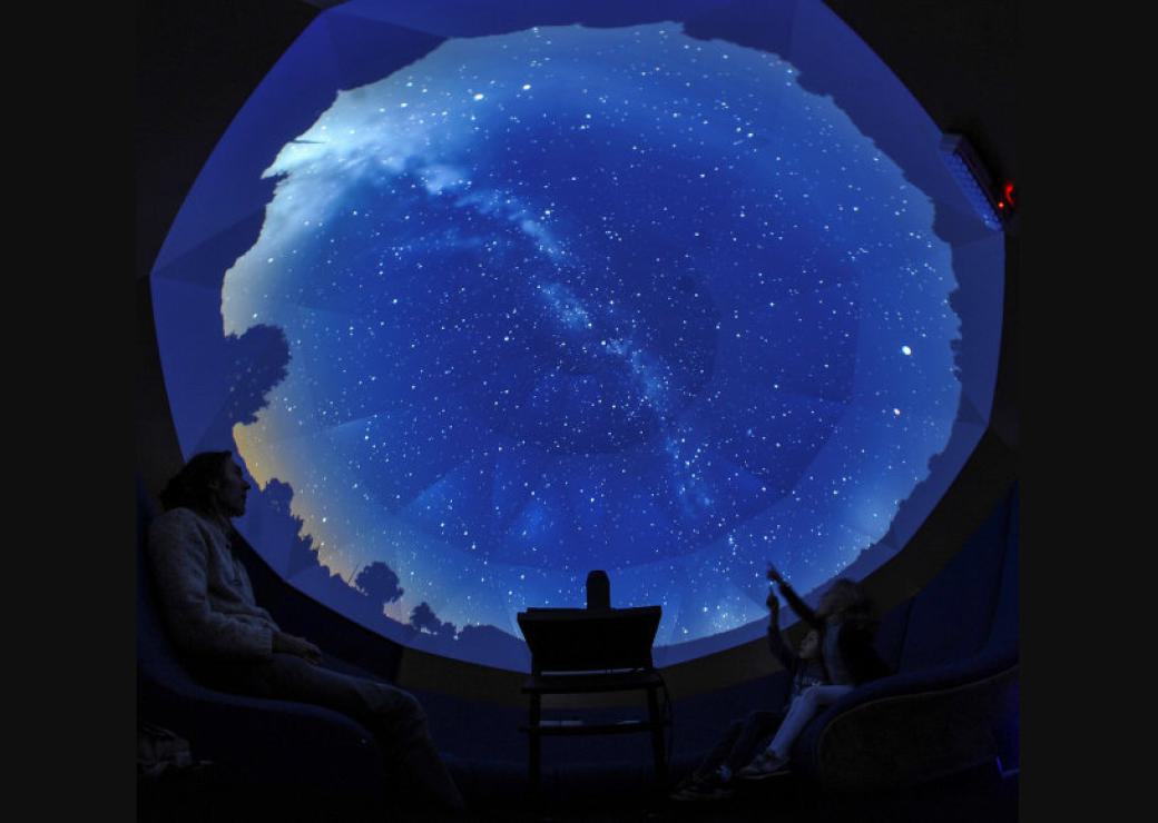 Un rond de ciel étoilé se démarque de l'ombre, avec des silhouettes de personnes