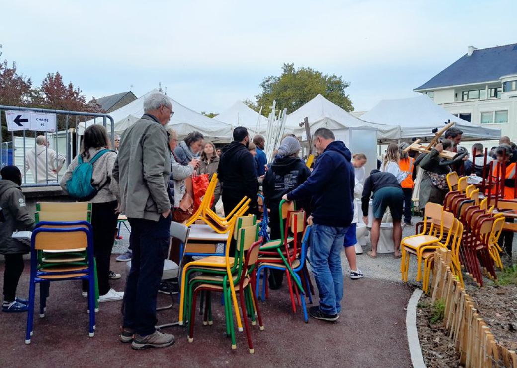 Une brocante en plein air, stocks de chaises et des personnes qui déambulent