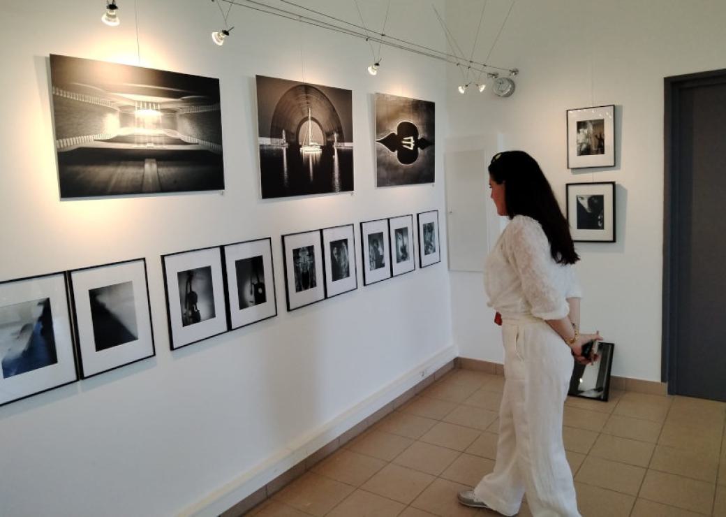 Un femme se tient face à des photos accrochées sur un mur blanc