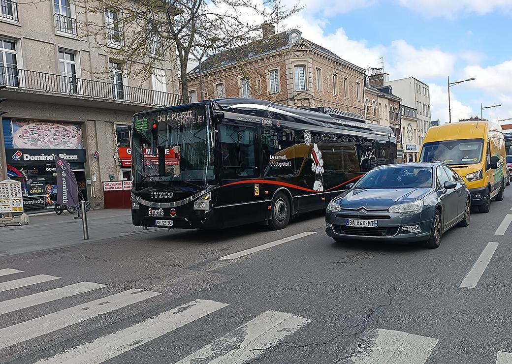 un bus biogaz , une voiture et une camionette en ville  