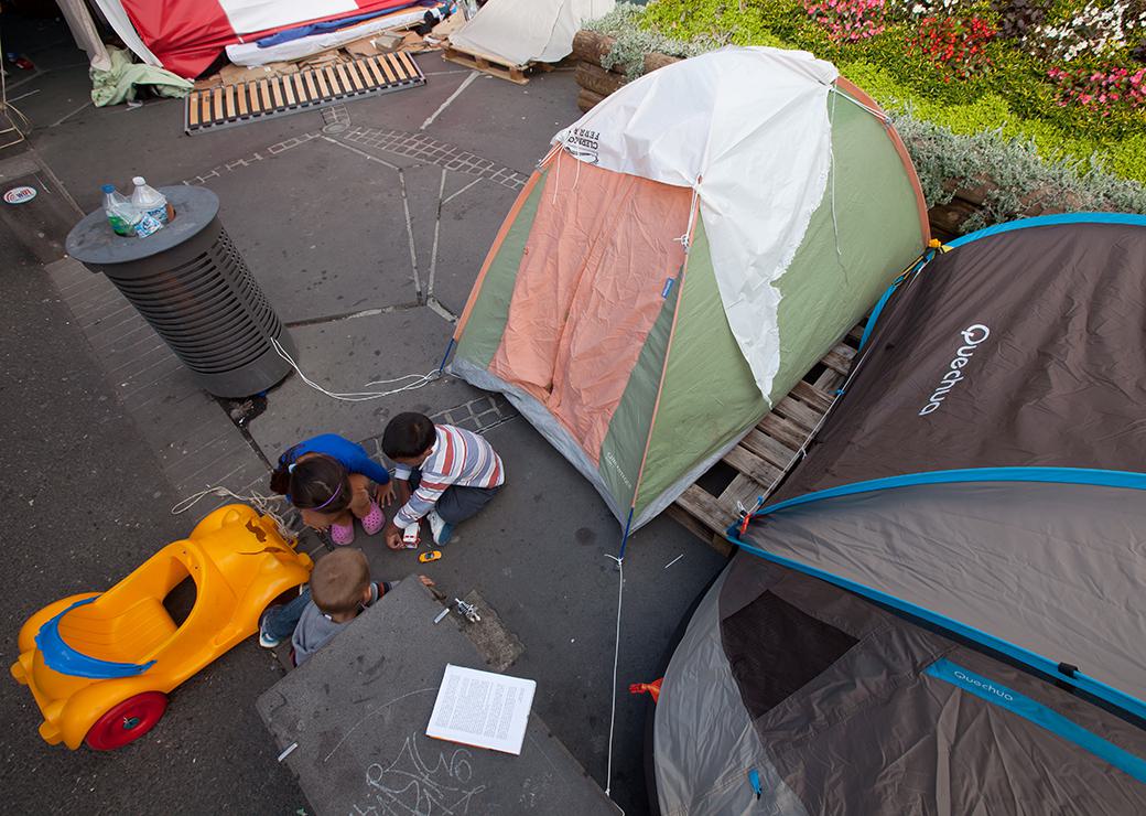des enfants jouent devant une tente dans la rue 
