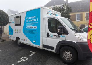 Un camion sur lequel est écrit medicobus est garé sur la place d'un village