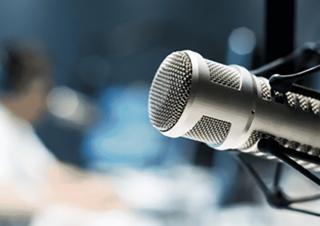 Gros plan sur un micro de radio, à l'arrière plan, une personne floue