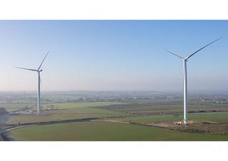 Vue aérienne d'un paysage vert où sont implantées deux éoliennes