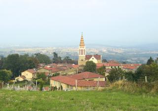 Vue en surplomb d'un village de maisons de pierre, avec en son centre un clocher.