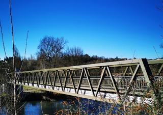 Vue oblique d'une passerelle métallique qui enjambe un cours d'eau