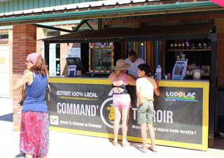 3 personnes attendent à un comptoir sur lequel on peut lire "Bistrot 100% local"