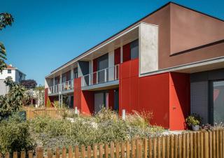 Vue d'un batiment d'un étage avec jardin et façade colorée en rouge