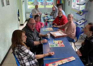 9 personnes se tiennent autour d'une table sur laquelle sont posés des jeux de société