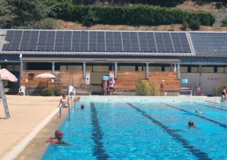 Une piscine de plein air, en arrière plan, le toit du bâtiment couvert de panneaux solaires