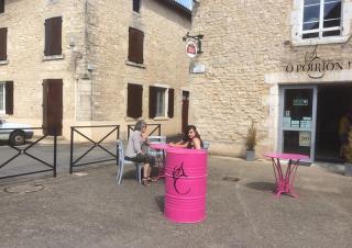 Deux femmes sont attablées à la table d'une terrasse, entourée de bâtiments aux pierres apparentes