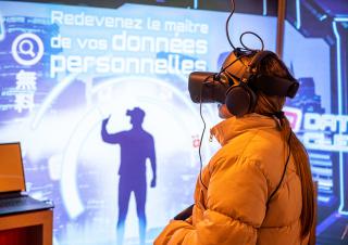 devant un écran sur lequel on peut lire "redevenez maitre de vos données personnelles", se tient une personne équipée d'un casque sur les yeux et les oreilles