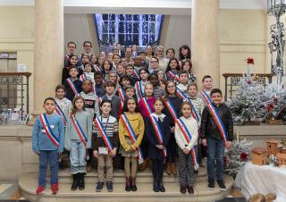 Sur les marches d'un escalier monumental, des enfants ceints d'une écharpe tricolore posent en groupe