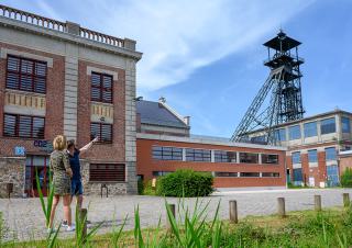 Un homme montre à une femme une tour métallique qui surplombe des bâtiments de brique rouge