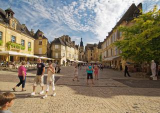 En été, un centre historique, des personnes en tenue estivale déambulent