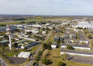 Vue aérienne d'une zone d'activité, avec des hangars et des bâtiments aux toits plats