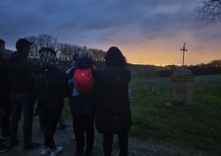 De nuit, nn groupe de 4 personnes, vues de dos, regarde en contrebas une ville éclairée