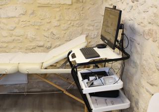 Une table d'auscultation à côté de laquelle est placée un écran d'ordinateur et un clavier