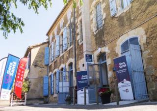 Une maison de village devant laquelle sont implantés des drapeaux où l'on peut lire "Centre de santé"