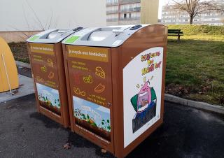 Bacs sur lesquels on peut lire "je recyle mes biodéchets", installés en pied d'immeuble