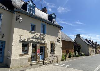 Façade d'une maison de village sur laquelle on peut lire "bar, épicerie, feste"