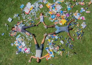 Vus d'en haut, deux adultes et deux enfants sont allongés sur une pelouse couverte de déchets d'emballage