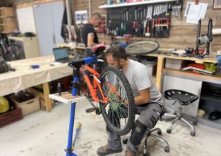 Dans un atelier, un homme répare un vélo