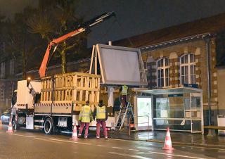 De nuit, un camion-grue démonte la structure d'un très grand panneau d'affichage