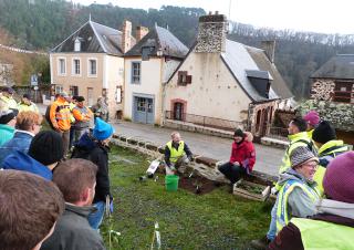 Un groupe de personnes regardent deux personnes qui plantent un végétal