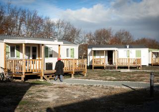 Deux mobiles homes. Une femme se dirige vers l'un de ces bâtiments