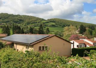 Vue aérienne d'un hangar dont le toit est couvert de panneaux solaire. Autour, paysage vert.
