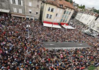 Vue aérienne d'une rue remplie de gens assis sur le sol, autour d'une portion de rue dégagée