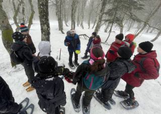 Des enfants autour d'un homme dans une forêt sous la neige