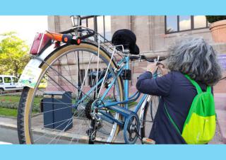 Une personne aux cheveux gris répare un vélo accroché en hauteur