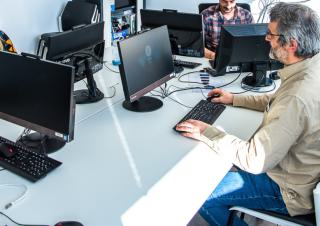 Trois personnes face à des écrans d'ordinateur