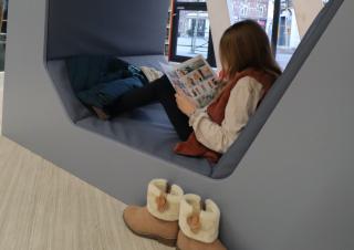 Une enfant lit une bande dessinée, installée dans une banquette en forme d'alvéole