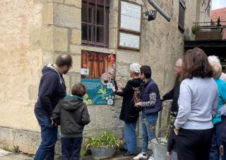 Des personnes regardent un panneau posé sur le mur d'une maison