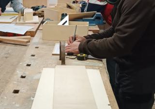 Plan resserré sur des main qui dessinent ou prennent des mesures sur du bois