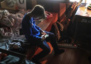 un enfant dans sa chambre regardant son télephone 