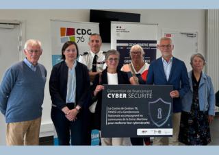 Des personnes se tiennent debout autour d'un panneau sur lequel on peut lire "convention financement cybersécurité"