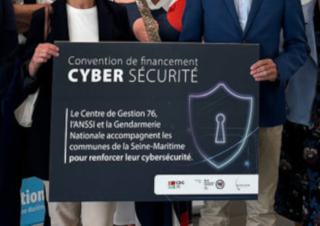 Un panneau tenu par des personnes. Sur le panneau on peut lire "convention de financement cybersécurité"