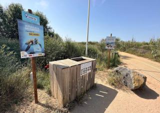 Des conteneurs bardés de bois à côté d'un chemin entre deux dunes
