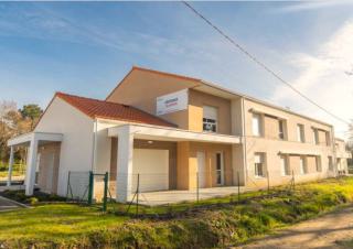 Une maison de deux étages de construction récente, avec de nombreuses fenêtre
