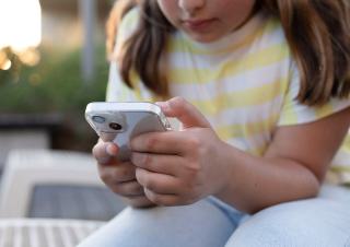 une pré adolescente regarde son téléphone 