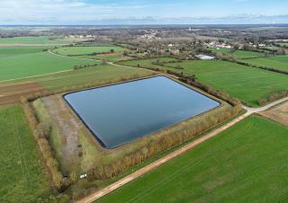 une megabassine au milieu de champs agricoles