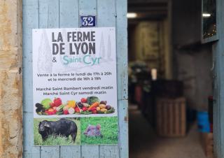 Porte de grange sur laquelle est apposée une affiche "ferme de Lyon"