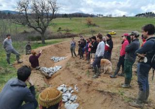 Un groupe de personne se tient sur le bord d'un fossé fraîchement creusé