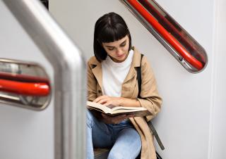 Une jeune fille en train de lire dans les transports 